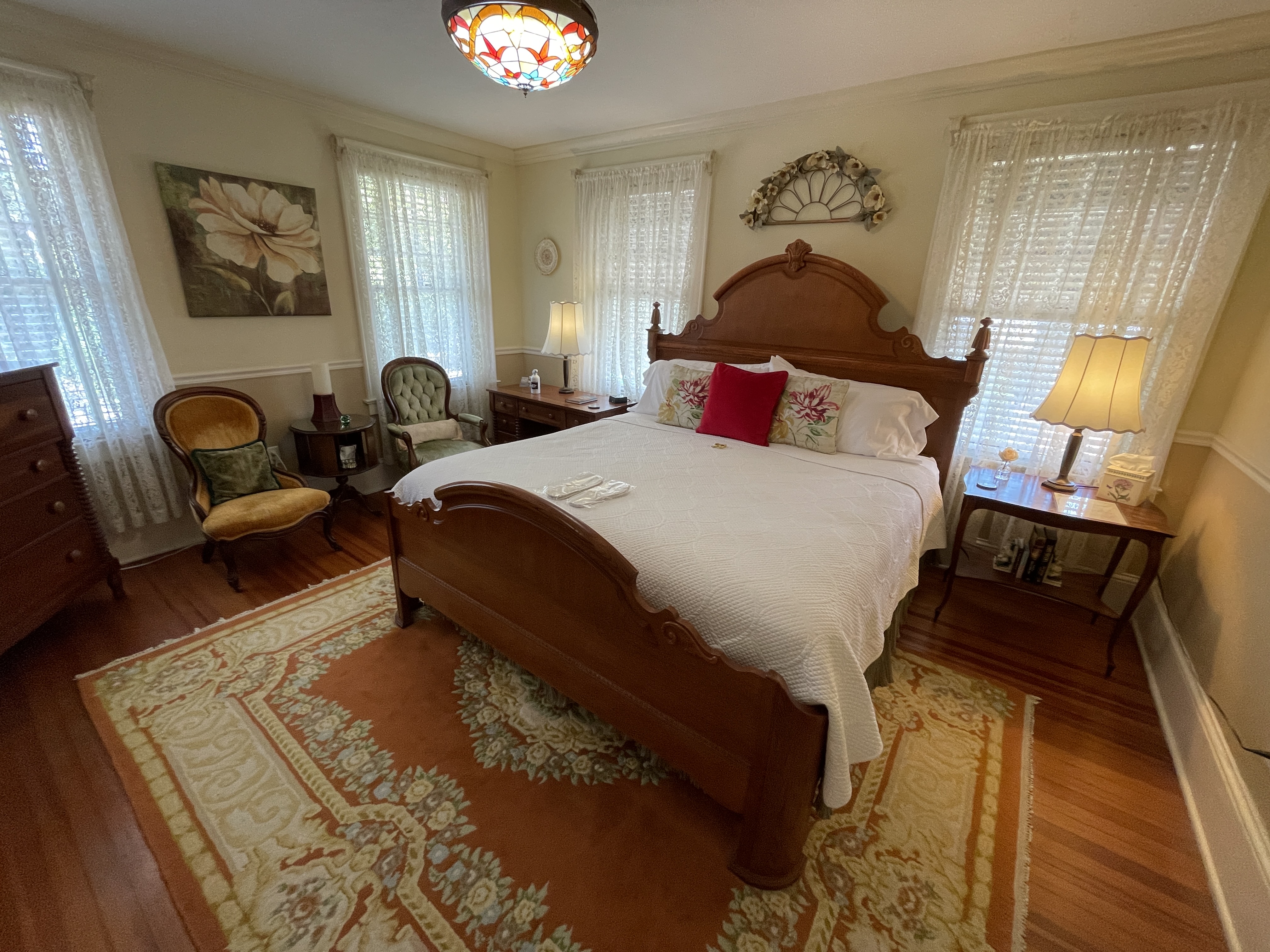 Charming bedroom with a beautiful wooden bed, antique furniture, and a vibrant rug. Enjoy a cozy atmosphere with ample natural light and classic decor.