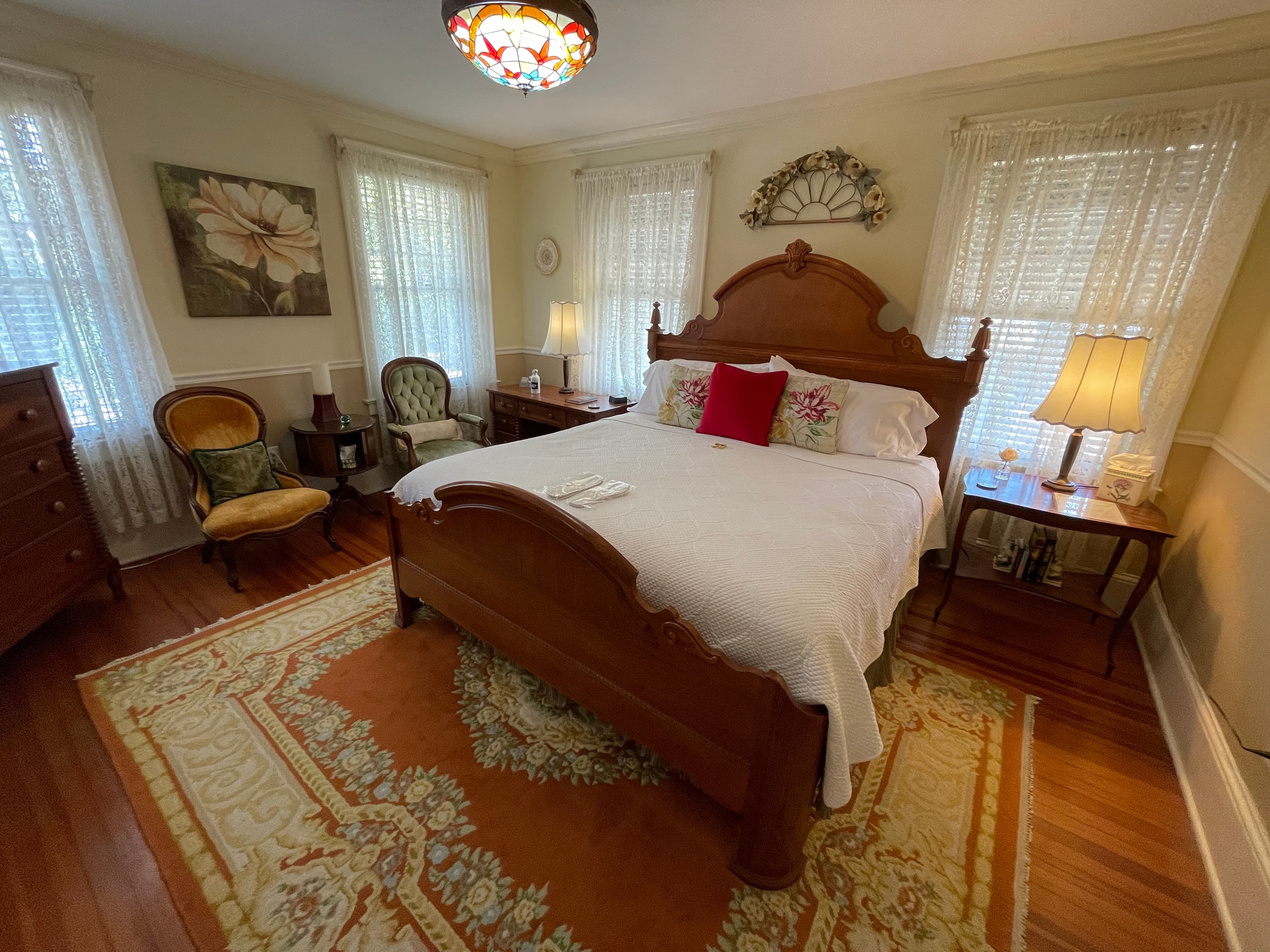 Charming bedroom with a beautiful wooden bed, antique furniture, and a vibrant rug. Enjoy a cozy atmosphere with ample natural light and classic decor.