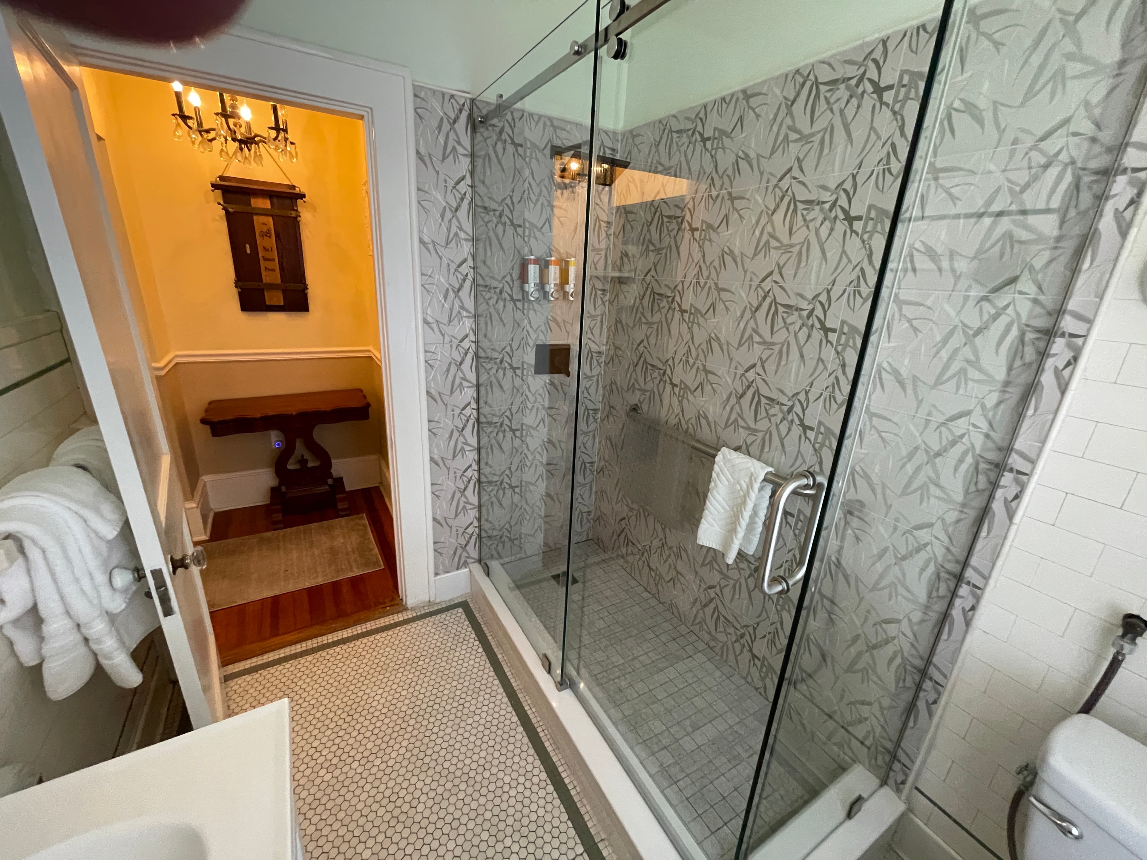 Spacious modern bathroom featuring a walk-in shower with unique patterned tiles and glass doors.