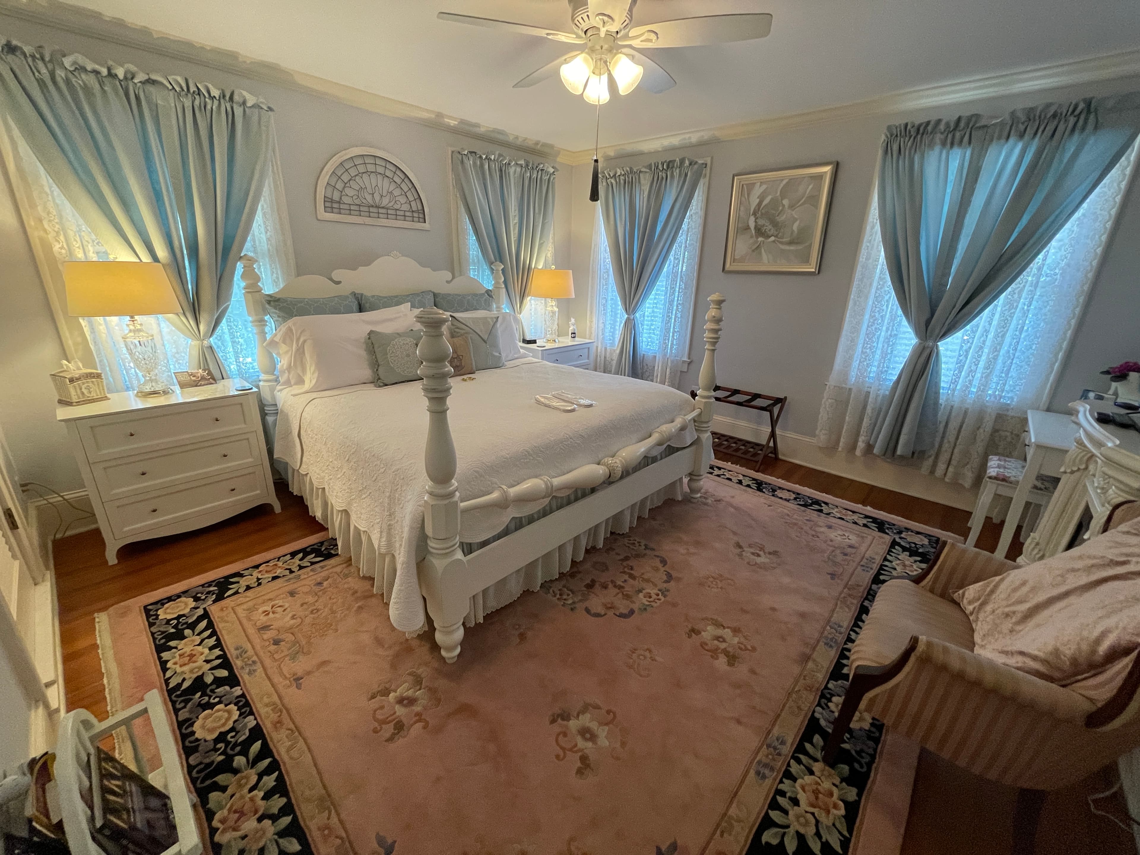 Serene bedroom with a beautiful four-poster bed, soft blue and pink accents, and classic white furnishings.