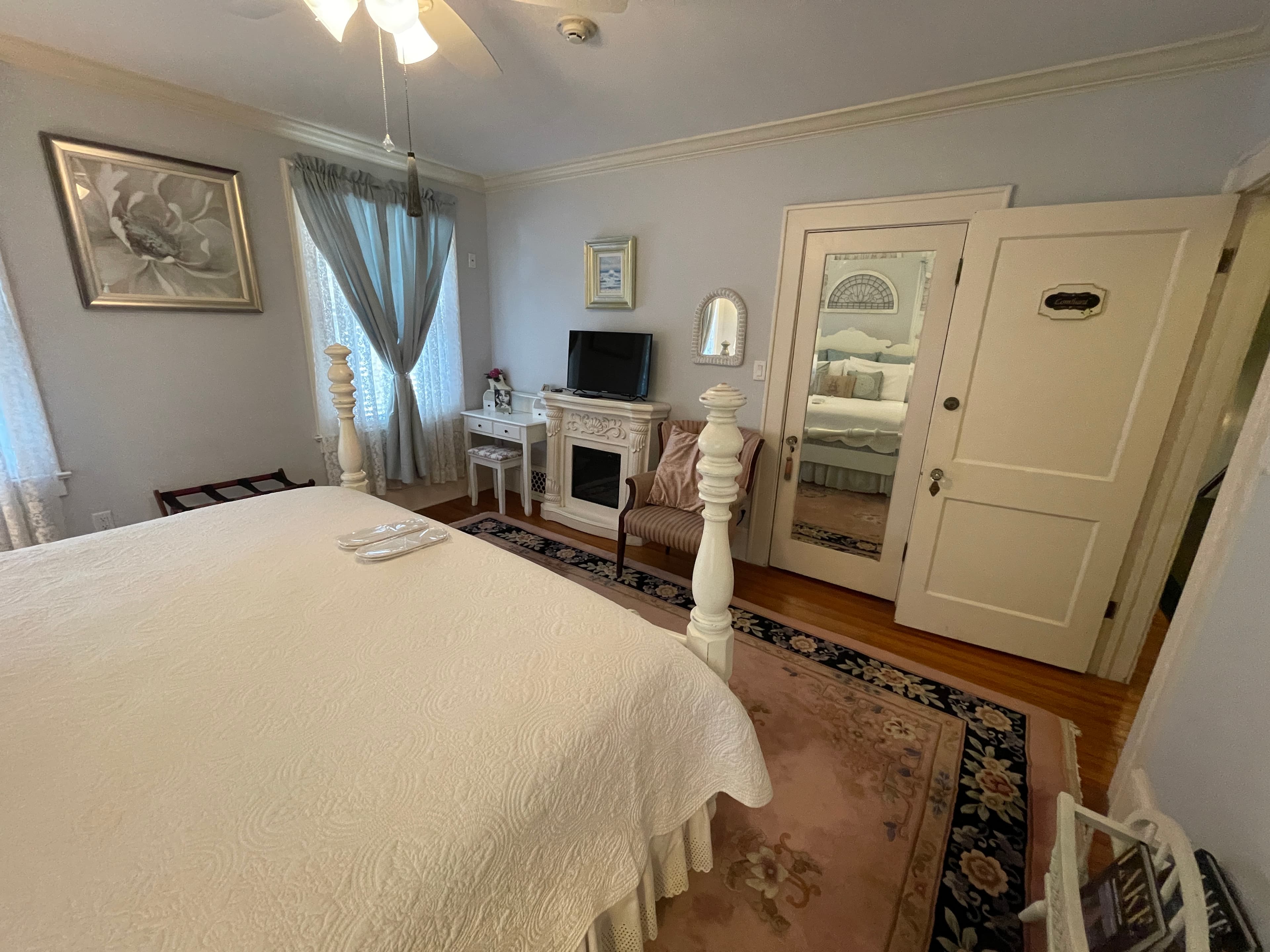 Charming bedroom with a cozy fireplace, comfortable bed, and elegant decor. Soft colors and a patterned rug create a serene and inviting ambiance.