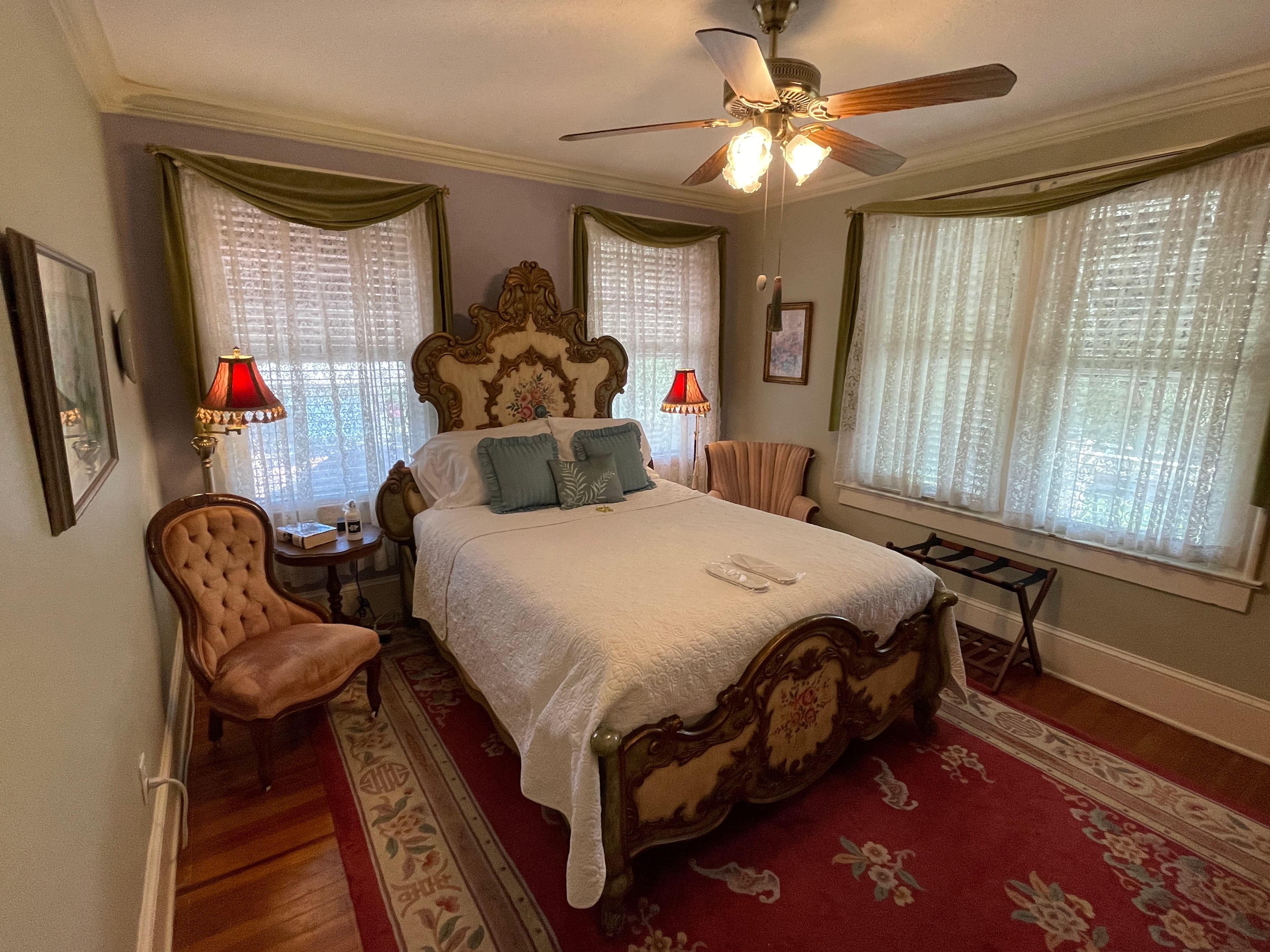 Luxurious bedroom featuring an ornate, gold-trimmed bed and rich red rug. Elegant furnishings and soft lighting create a romantic and opulent retreat.