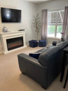 Cozy living room with a comfortable sofa, warm fireplace, and a mounted TV for entertainment.